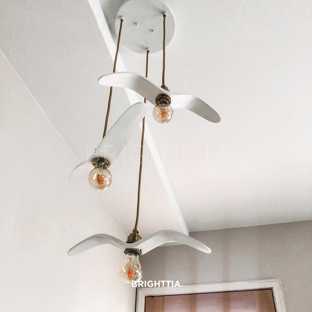 A custom 3-light white abstract flying bird pendant made with three brass shade-ready E26 bulb sockets