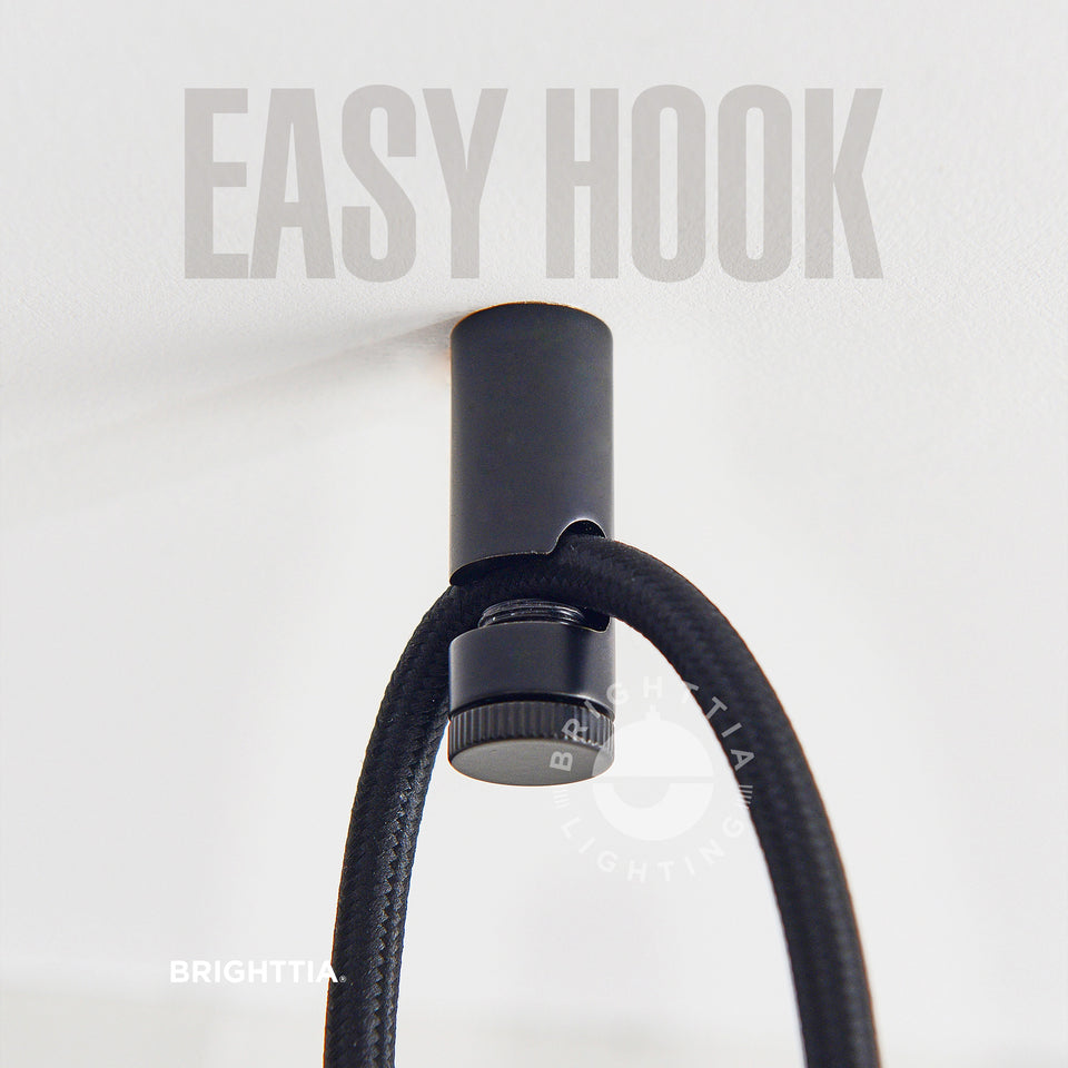 Brighttia Easy Hook in black mounted on white ceiling with a black fabric cord hanging on it.