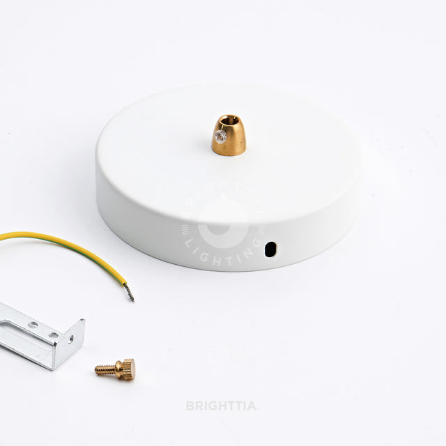 Cone-shaped brass cord grip used on white ceiling canopy with mounting bracket by the side on white surface.