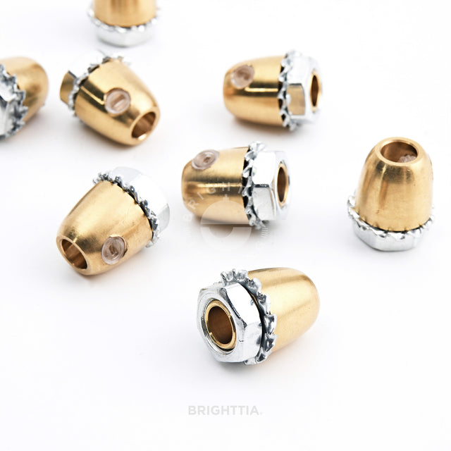 Cone-shaped brass cord grips scattered randomly on white surface.
