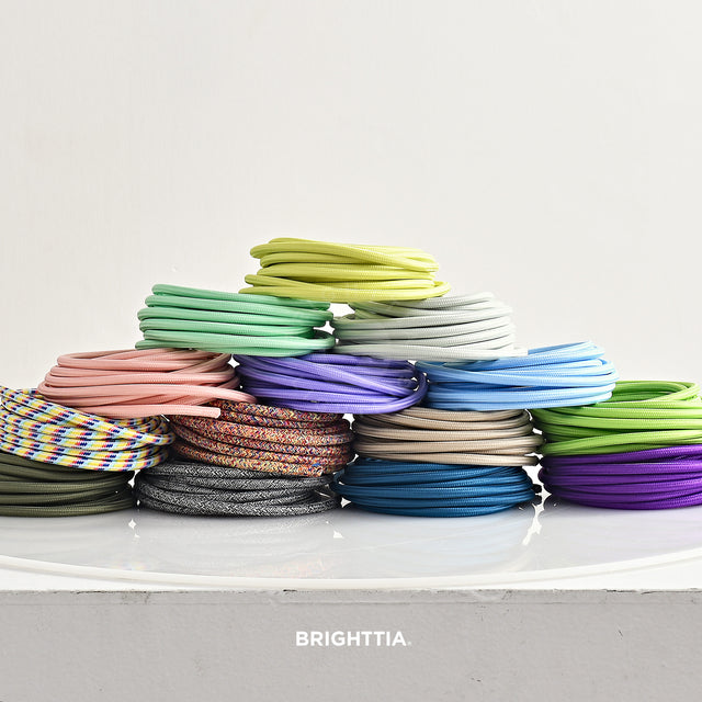 Group of solid round color cords in rolls stacked up on white surface viewed straight on.