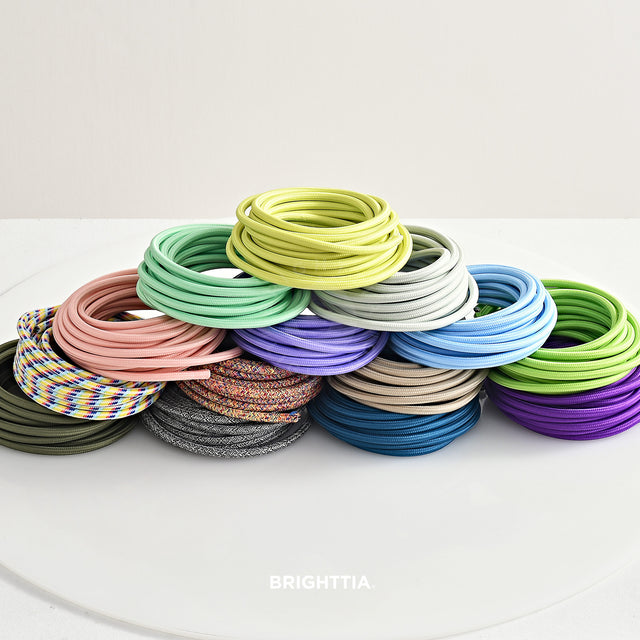 Group of solid round color cords in rolls stacked up on white surface.