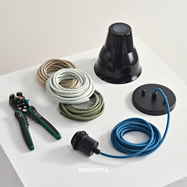 Making a black shade-ready pendant light fixture with an aegean blue fabric cords on white surface with three rolls of muted color cord and wire stripper by the side
