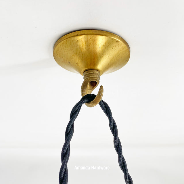Brass ceiling hook with black cord on a white background