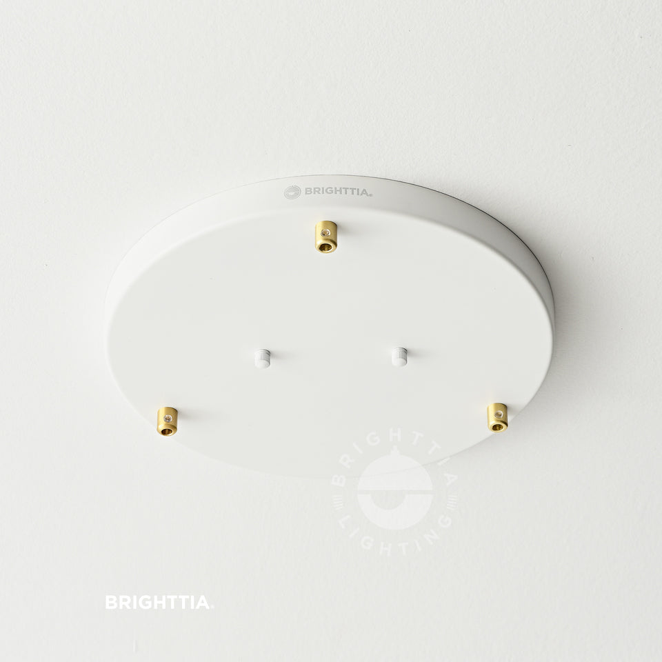 A 12inch 3-port white ceiling canopy with cylindrical brass cord grips mounted on white ceiling.