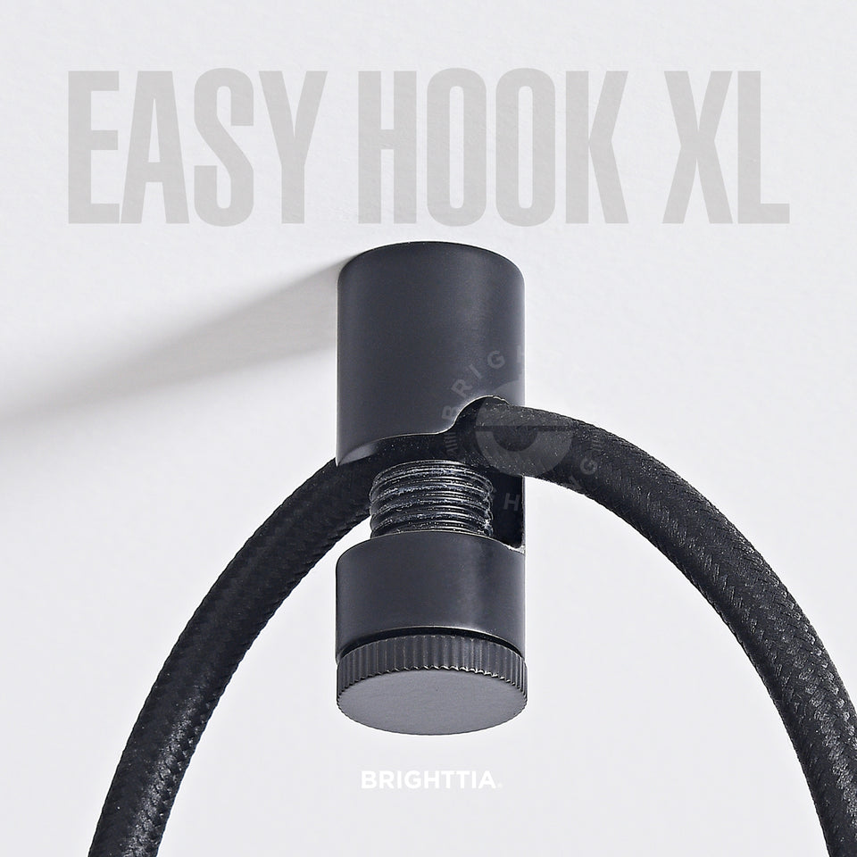 A black easy hook XL mounted on white ceiling with a black fabric cord hanging on it.