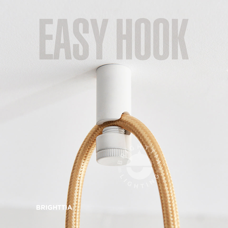 Brighttia Easy Hook in white mounted on white ceiling with a gold fabric cord hanging on it.