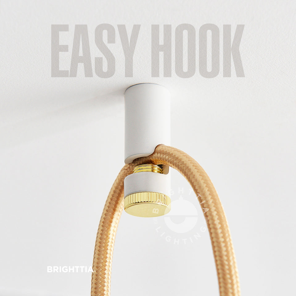 Brighttia Easy Hook in white & gold mounted on white ceiling with a gold fabric cord hanging on it.