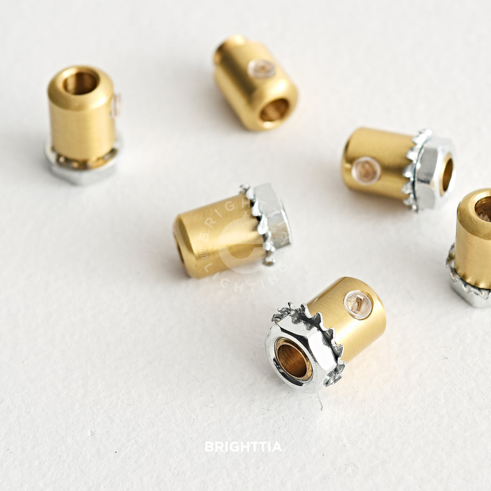 Cylinder brass cord grips scattered randomly on white surface.