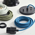 Making a black pendant light fixture with an aegean blue fabric cords on white surface with three rolls of muted color cord by the side